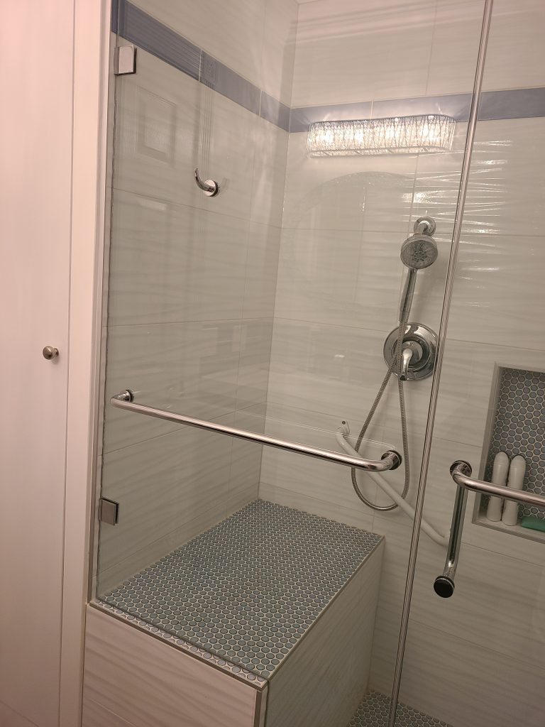 After: low-entry glass shower with built-in bench and grab bars
